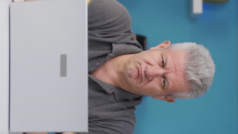 Vertical-video-of-Home-office-worker-man-looking-nervously-at-camera.